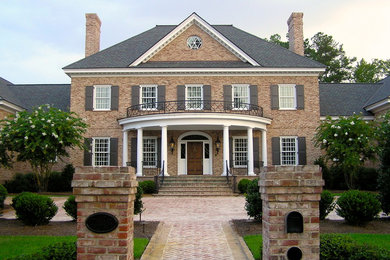 Large traditional red two-story brick exterior home idea in Other with a hip roof