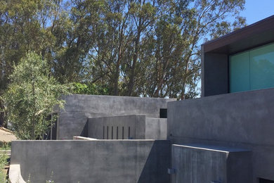 Example of a large minimalist gray three-story stucco exterior home design in Orange County
