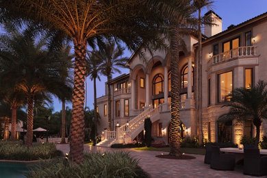 This is an example of an expansive and beige classic concrete house exterior in Tampa with three floors and a pitched roof.