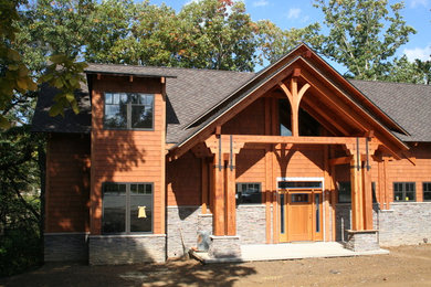 Imagen de fachada de casa de estilo americano de dos plantas con revestimientos combinados, tejado a dos aguas y tejado de teja de madera