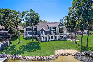 Example of a huge beach style gray two-story stone exterior home design in Milwaukee with a shingle roof