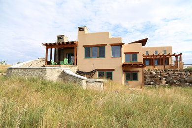 Foto de fachada de casa beige de estilo americano de tamaño medio de dos plantas con revestimiento de adobe, tejado plano y tejado de metal