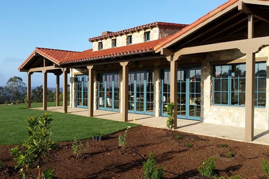 Mid-sized tuscan beige two-story stone exterior home photo in Los Angeles with a hip roof