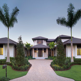 Island style white two-story stucco exterior home photo in Miami with a hip roof and a tile roof