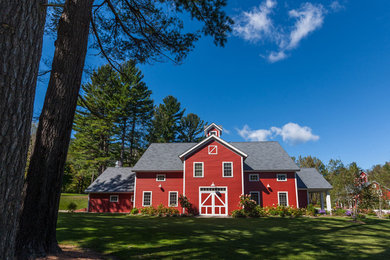 Foto della villa grande rossa country a due piani con rivestimento in legno, tetto a capanna e copertura a scandole