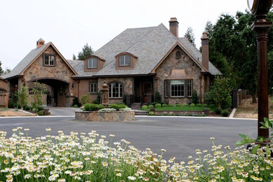Diseño de fachada de casa beige clásica grande de dos plantas con revestimiento de piedra