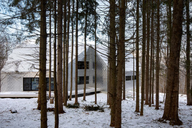 Diseño de fachada de casa contemporánea de tamaño medio de dos plantas con revestimiento de metal, tejado a dos aguas y tejado de metal