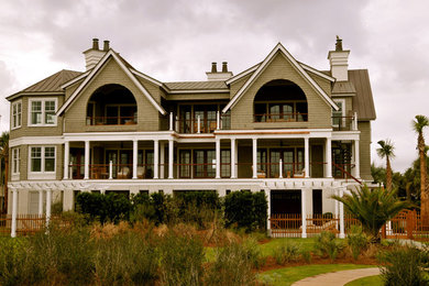 Diseño de fachada verde marinera grande de tres plantas con revestimiento de madera