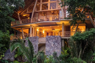 ハワイにあるトロピカルスタイルのおしゃれな家の外観 (ガラスサイディング) の写真