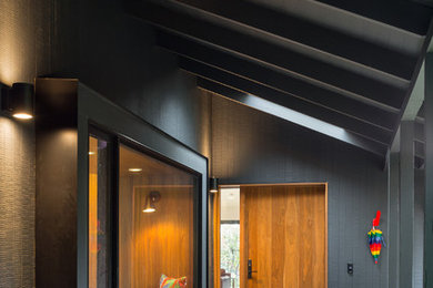 Inspiration for a mid-sized mid-century modern black one-story wood exterior home remodel in Portland with a metal roof