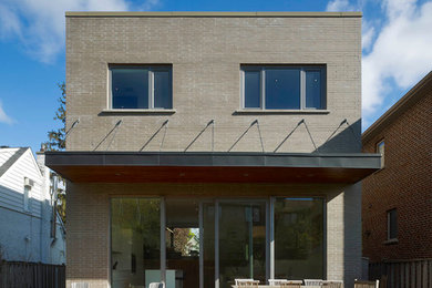 Inspiration for a mid-sized contemporary gray two-story brick flat roof remodel in Toronto
