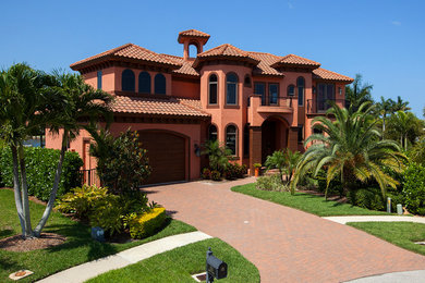 Свежая идея для дизайна: двухэтажный, красный дом в средиземноморском стиле с облицовкой из цементной штукатурки и вальмовой крышей - отличное фото интерьера