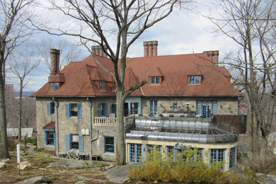 Modelo de fachada de casa beige tradicional grande de tres plantas con revestimiento de piedra, tejado a cuatro aguas y tejado de teja de madera