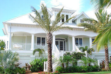 Large beach style white two-story wood house exterior photo in Miami with a hip roof and a metal roof
