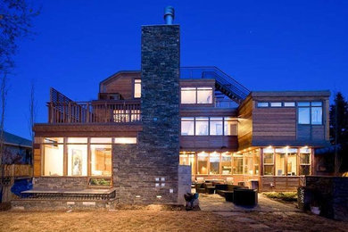 Photo of an expansive rustic house exterior in Calgary with three floors and wood cladding.