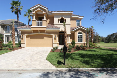 Example of a large tuscan beige two-story stucco exterior home design in Orlando with a tile roof