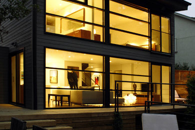 Ejemplo de fachada de casa gris minimalista de dos plantas con revestimiento de madera, tejado de un solo tendido y tejado de metal