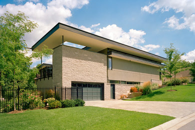 Foto de fachada de casa beige minimalista grande a niveles con revestimiento de piedra, tejado plano y tejado de metal