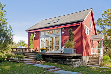 Imagen de fachada roja campestre grande de tres plantas con revestimiento de madera y tejado a dos aguas