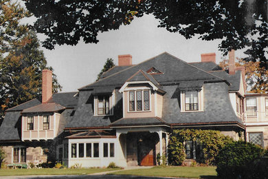 Modelo de fachada de casa beige de estilo americano grande de dos plantas con revestimientos combinados, tejado a dos aguas y tejado de teja de madera