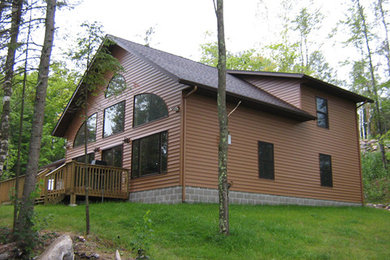 Example of a large mountain style brown two-story vinyl exterior home design in Other with a gambrel roof