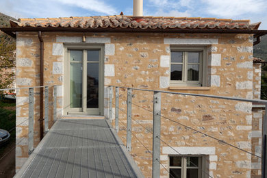Foto de fachada rústica con revestimiento de piedra y tejado de teja de barro