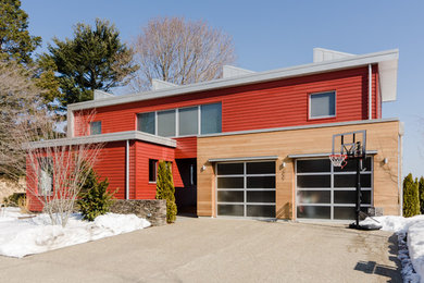 Foto på ett mellanstort funkis rött hus, med två våningar, blandad fasad, valmat tak och tak i metall