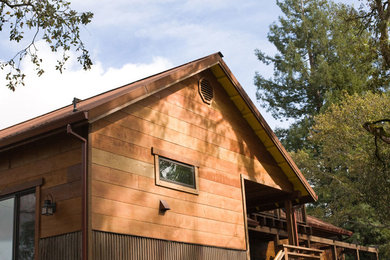Foto della villa a due piani con rivestimento in legno, tetto a capanna e copertura in metallo o lamiera