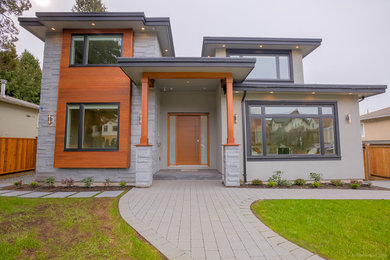 Inspiration pour une grande façade de maison grise design en bois à deux étages et plus avec un toit à quatre pans.