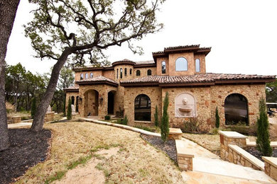 Large mediterranean beige two-story stone exterior home idea in Austin