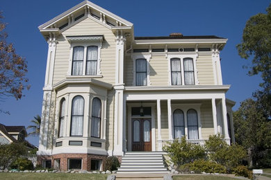 Modelo de fachada de casa beige clásica de tamaño medio de dos plantas con revestimiento de madera