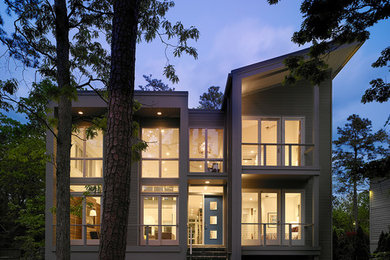 Cette image montre une très grande façade de maison grise minimaliste en bois à un étage avec un toit plat.