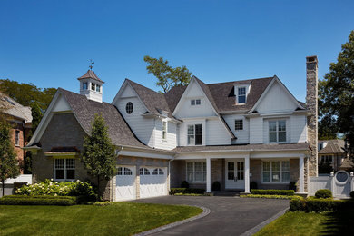 Zweistöckiges Landhausstil Einfamilienhaus mit Steinfassade, weißer Fassadenfarbe und Schindeldach in Chicago