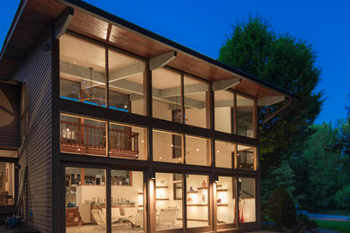 Inspiration for a large contemporary brown two-story wood house exterior remodel in New York with a shed roof