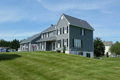 Imagen de fachada de casa gris clásica grande de dos plantas con revestimiento de vinilo, tejado a dos aguas y tejado de teja de madera