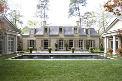 Пример оригинального дизайна: большой, двухэтажный, серый дом в классическом стиле с облицовкой из цементной штукатурки и двускатной крышей