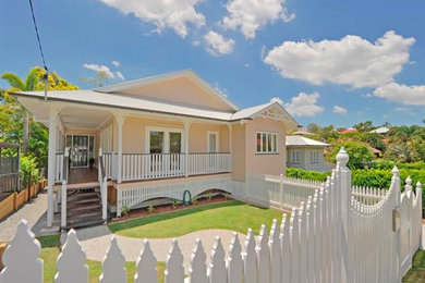 Medium sized and beige classic bungalow house exterior in Brisbane with wood cladding and a pitched roof.