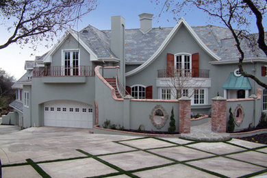 Immagine della facciata di una casa grande grigia classica a tre piani con tetto a capanna e rivestimento in stucco