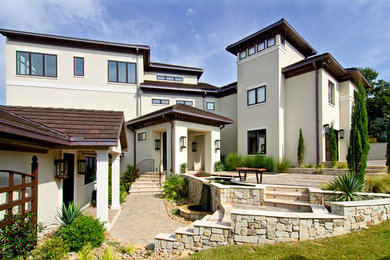 Идея дизайна: большой, трехэтажный, бежевый дом в современном стиле с облицовкой из цементной штукатурки и вальмовой крышей