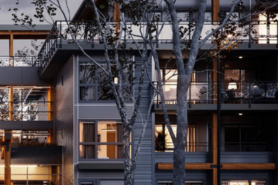 Large trendy gray four-story wood exterior home photo in Vancouver with a mixed material roof