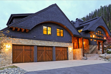 Idée de décoration pour une grande façade de maison noire chalet en bois à un étage avec un toit à deux pans et un toit en shingle.