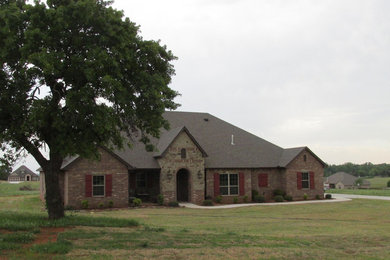 Example of a large classic brown one-story brick exterior home design in Oklahoma City with a hip roof