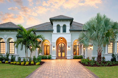 Large elegant gray one-story stucco house exterior photo in Orlando with a hip roof and a shingle roof