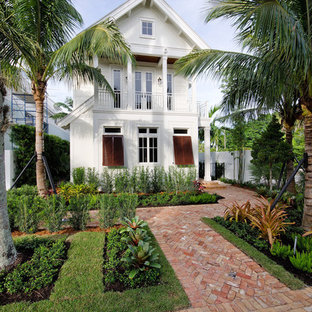 Immagine della villa bianca tropicale a due piani di medie dimensioni con tetto a capanna e copertura in metallo o lamiera