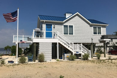 Mid-sized beach style gray two-story wood house exterior photo in New York with a hip roof and a metal roof