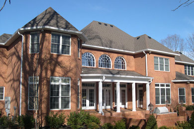 Example of a large classic brown two-story brick house exterior design in Nashville with a hip roof and a shingle roof