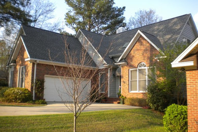 Example of a classic red one-story brick gable roof design in Charleston