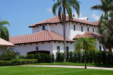 Diseño de fachada blanca mediterránea grande de dos plantas con revestimiento de estuco, tejado a cuatro aguas y tejado de teja de barro