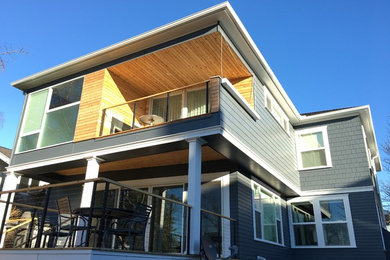 Exemple d'une façade de maison grise moderne de taille moyenne et à un étage avec un revêtement en vinyle et un toit à quatre pans.