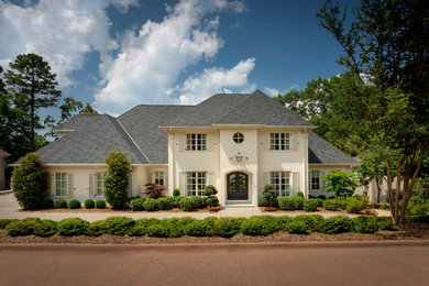 Large transitional beige two-story stone house exterior photo in Little Rock with a hip roof and a shingle roof